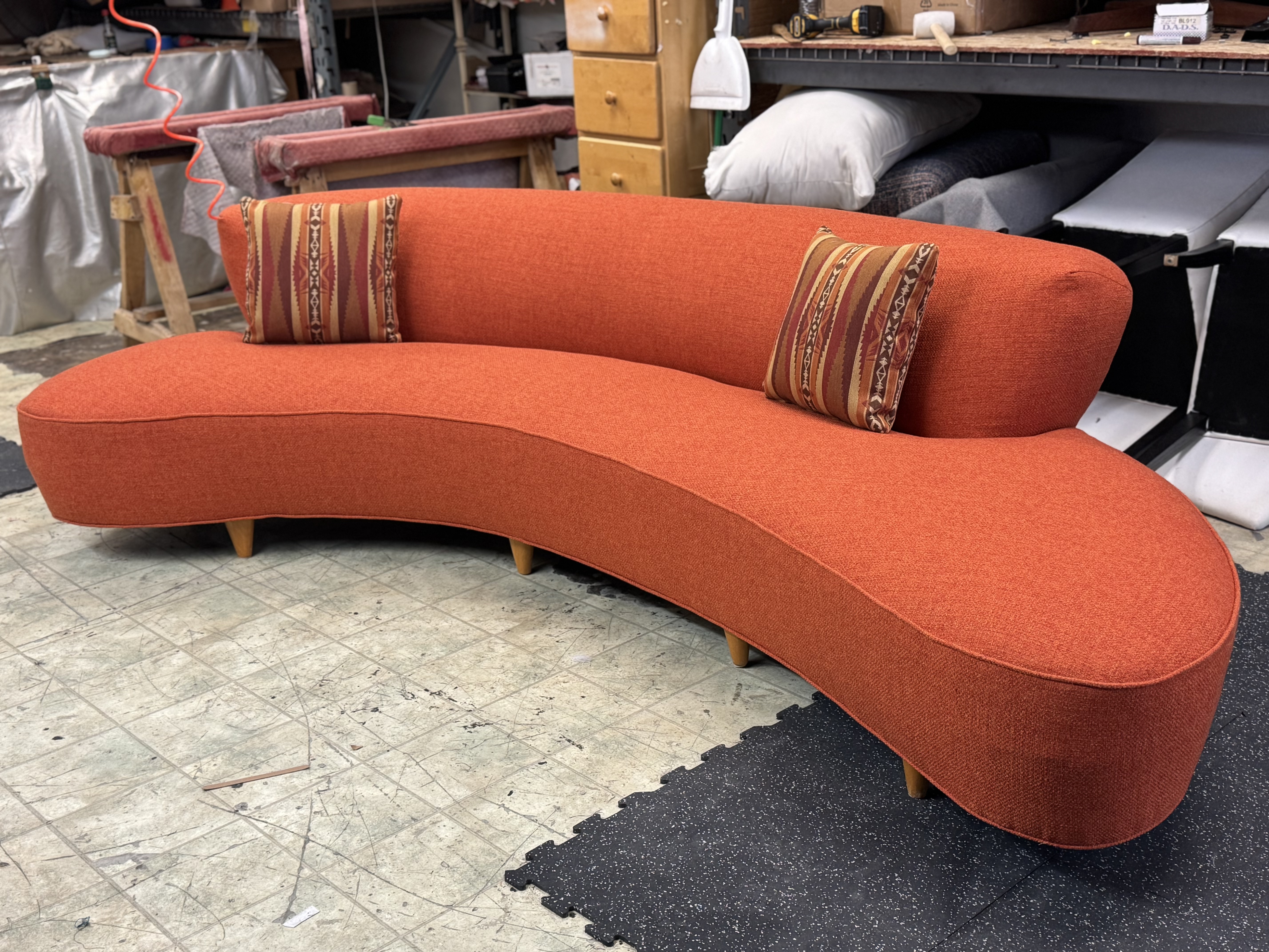 Orange Sofa with natural wood legs and 2 18 x 18 pillows in a pattern similar color.