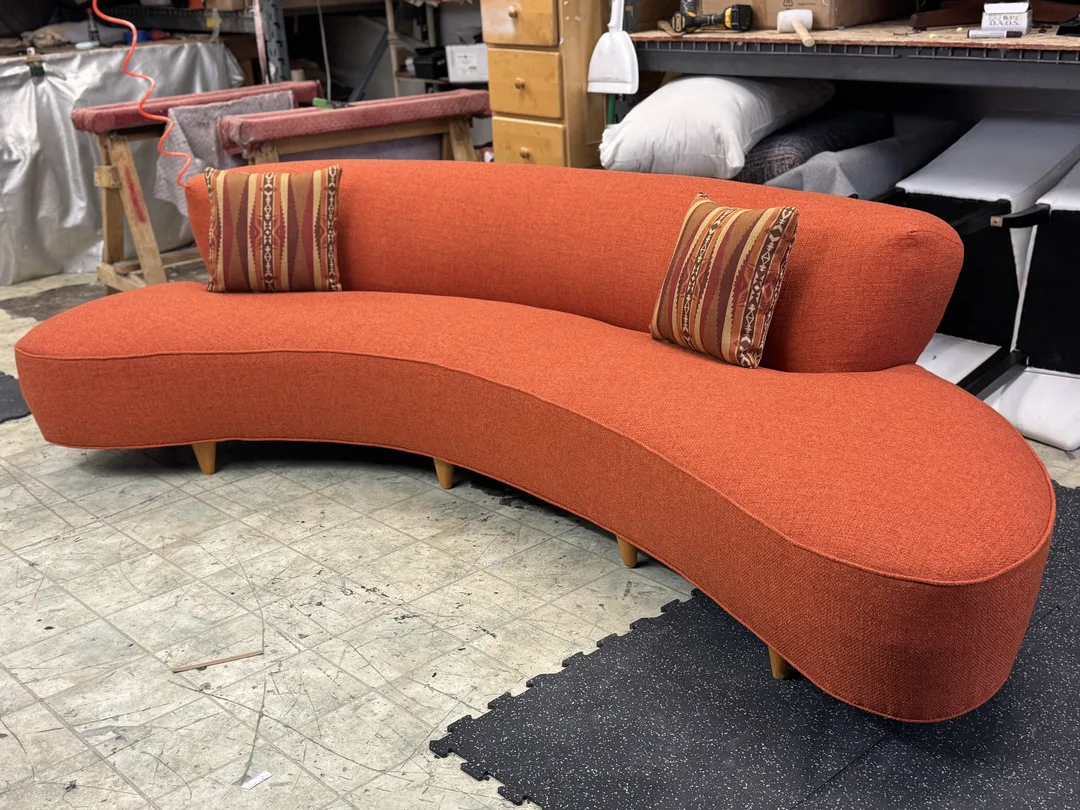 Orange Sofa with natural wood legs and 2 18 x 18 pillows in a pattern similar color.